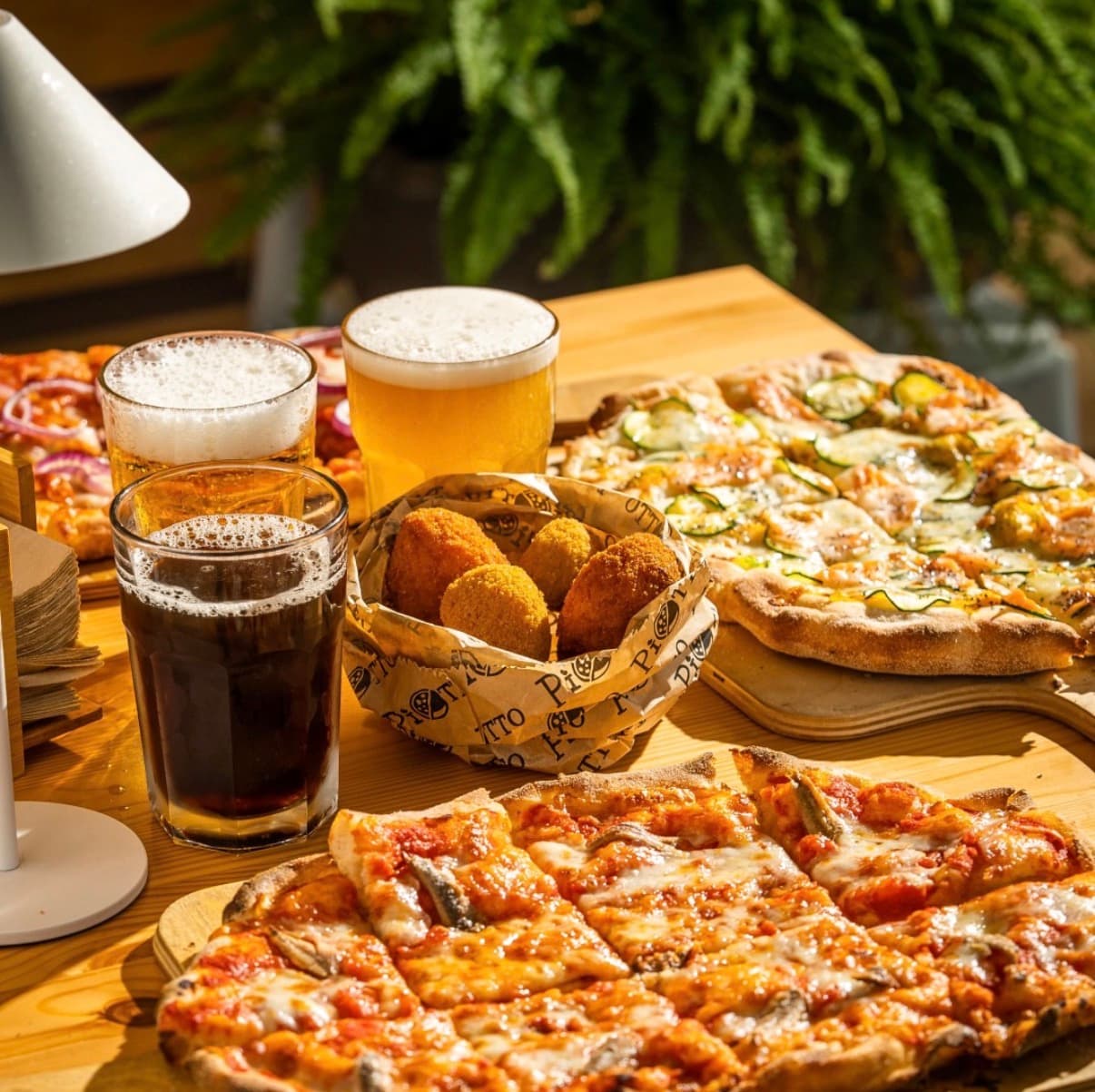 Un tavolo apparecchiato con pinse, fritti e birra